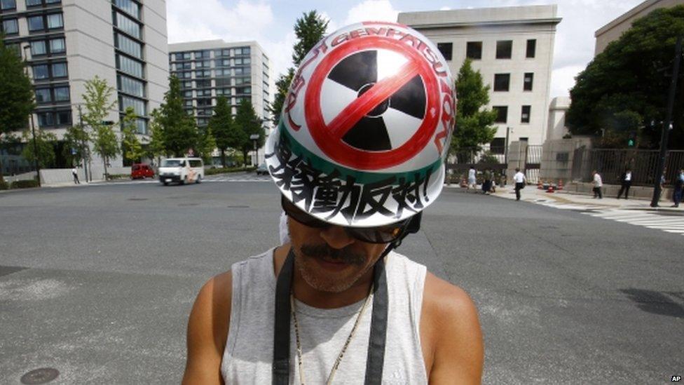 A protester checks a mobile phone during an anti-nuclear rally in front of Prime Minister Shinzo Abe"s official residence in Tokyo, Tuesday, 11 Aug 2015