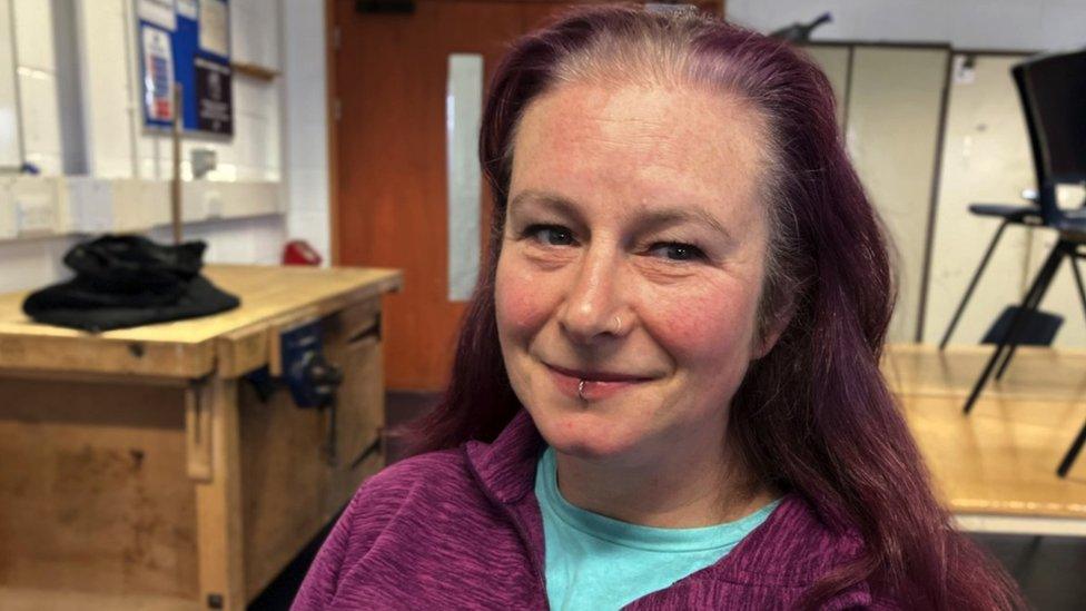 Image of Zoe Cormack. She has long, dark red hair and is wearing a bright turquoise top with a purple jacket. She is looking directly at the camera and smiling.