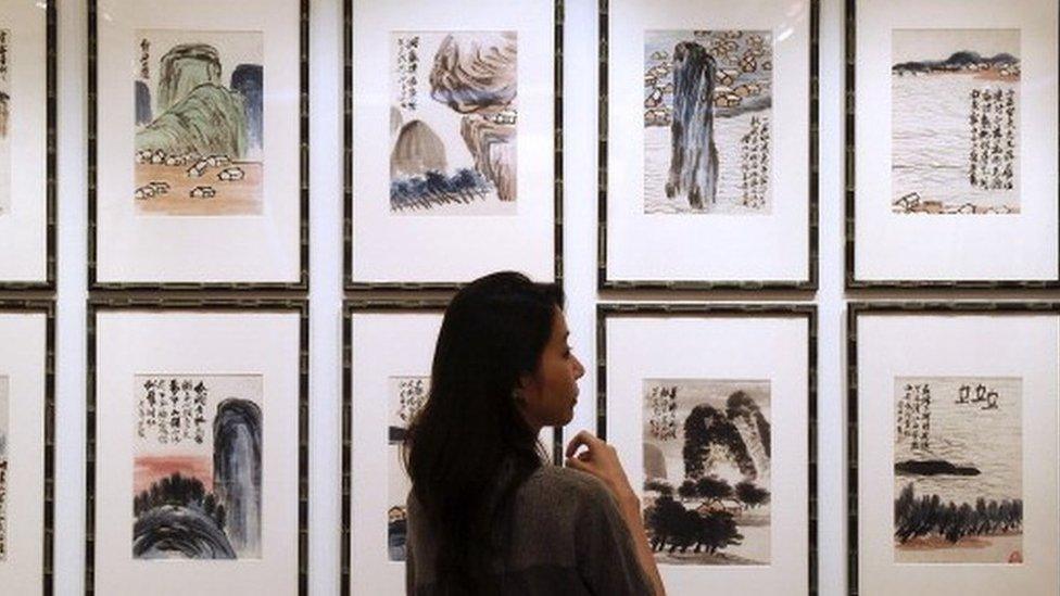 A woman inspects artwork by Chinese artist Qi Baishi entitled 'Landscapes' during a China Guardian auction preview in Hong Kong.