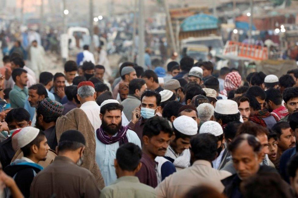 A man wearing a protective mask walks through a crowd of people along a makeshift market as the outbreak of the coronavirus disease (COVID-19) continues, in Karachi, Pakistan January 17, 2021.