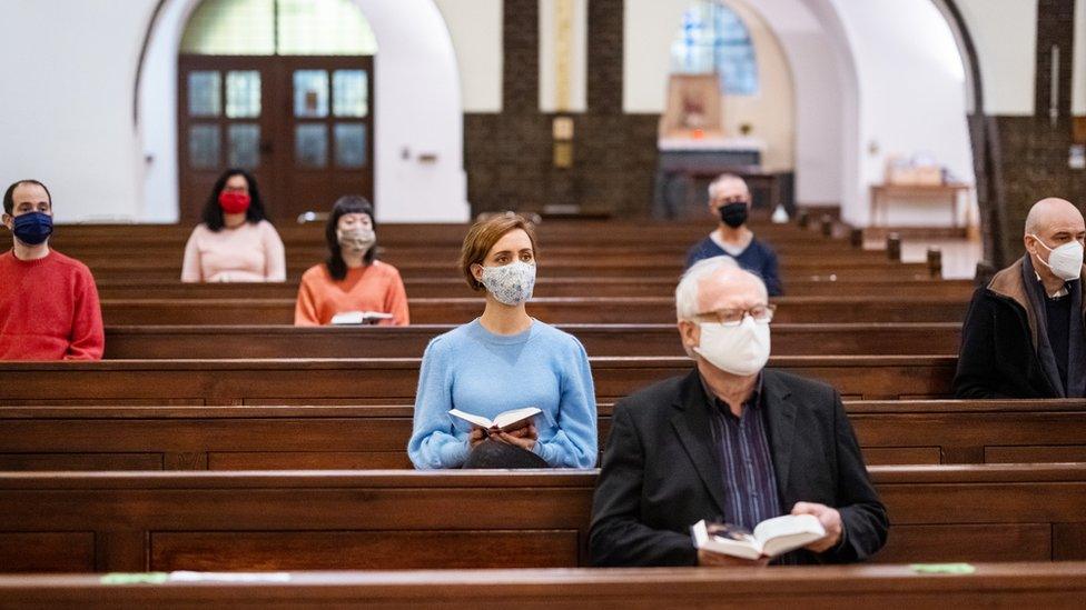 People wearing masks socially distance in a church