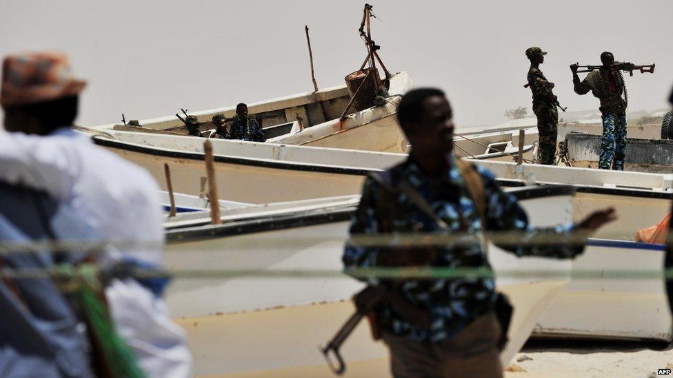 Armed militiamen and some pirates stand among fishing boats on the coast in the central Somali town of Hobyo on August 20, 2010.