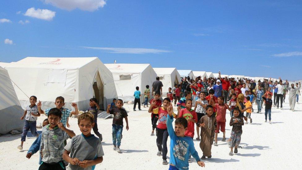 Displaced Syrians take part in a protest at a camp for displaced people in Kafr Lusin near the Bab al-Hawa border crossing with Turkey on September 7, 2018