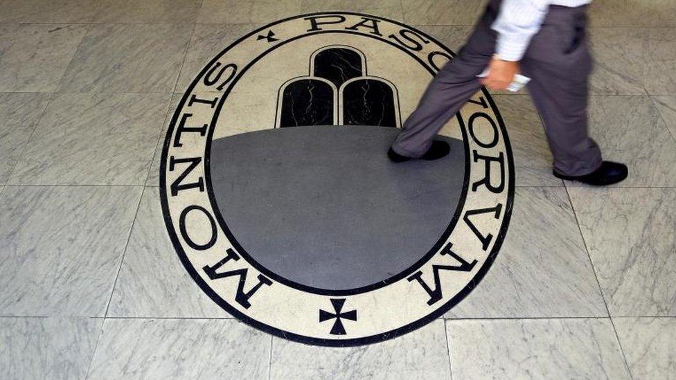 A man walks on a logo of the Monte Dei Paschi Di Siena bank