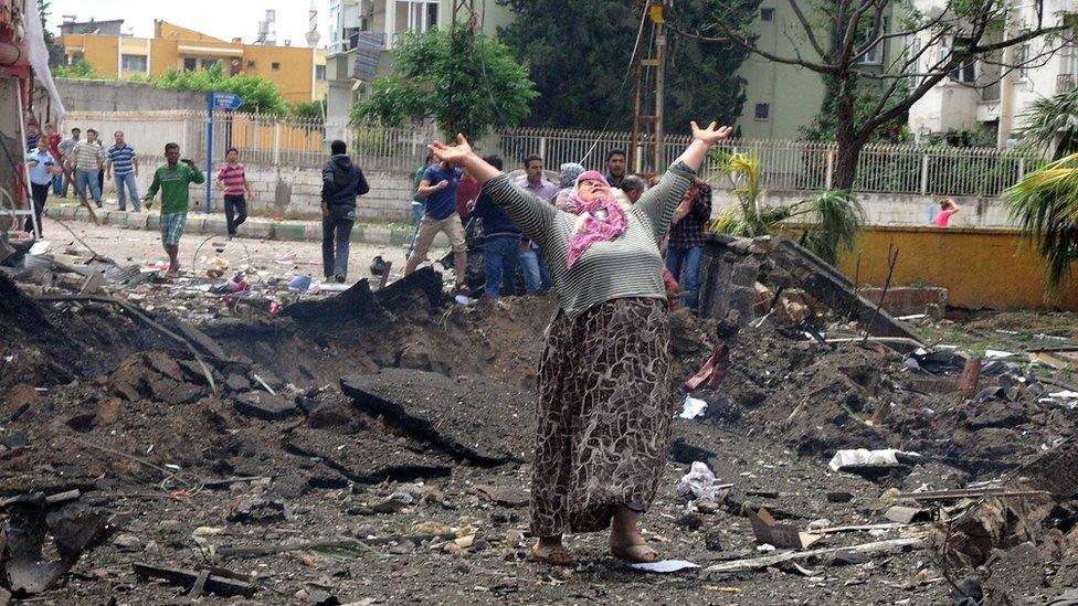 A woman raises her arms at the site of one of the bombs that exploded in Reyhanli, Turkey, on 11 May 2013