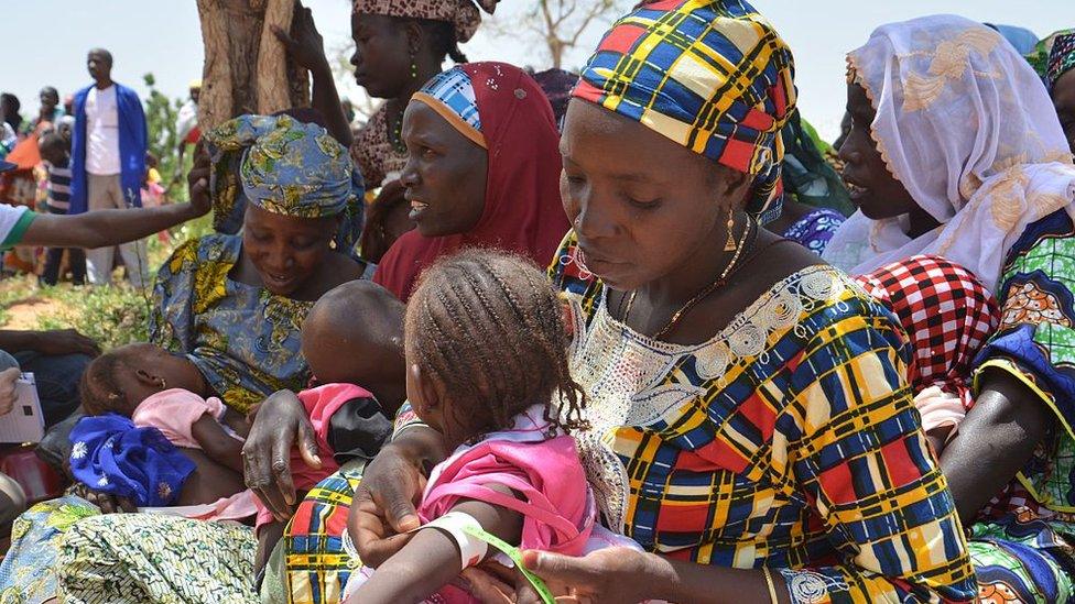 A Nigerien mother uses a MUAC (mid-upper arm circumference) measuring tape, during local malnutrition education on July 14, 2016 in the southern village of Barago