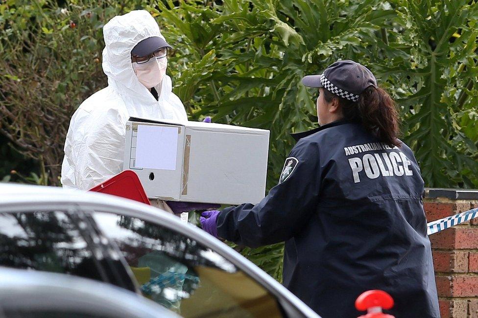 Investigators carry a box of evidence from the house gunman Yacqub Khayre is believed have shared with his mother