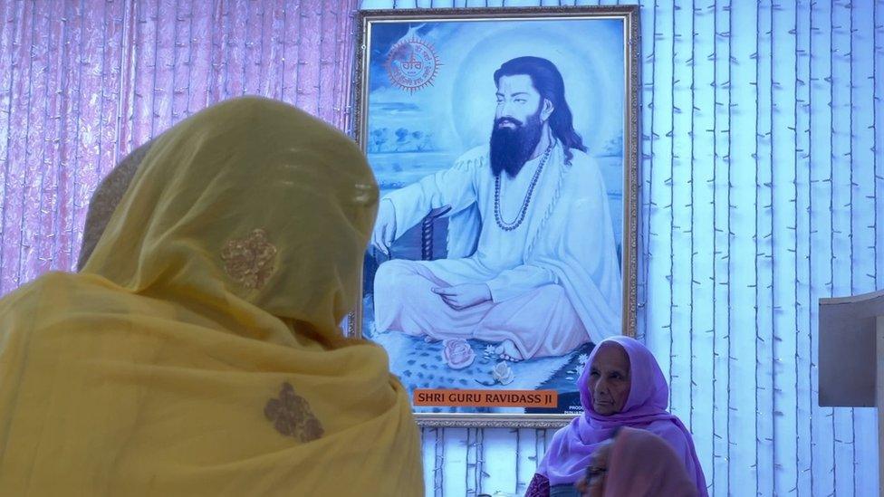 Worshippers sitting next to a painting