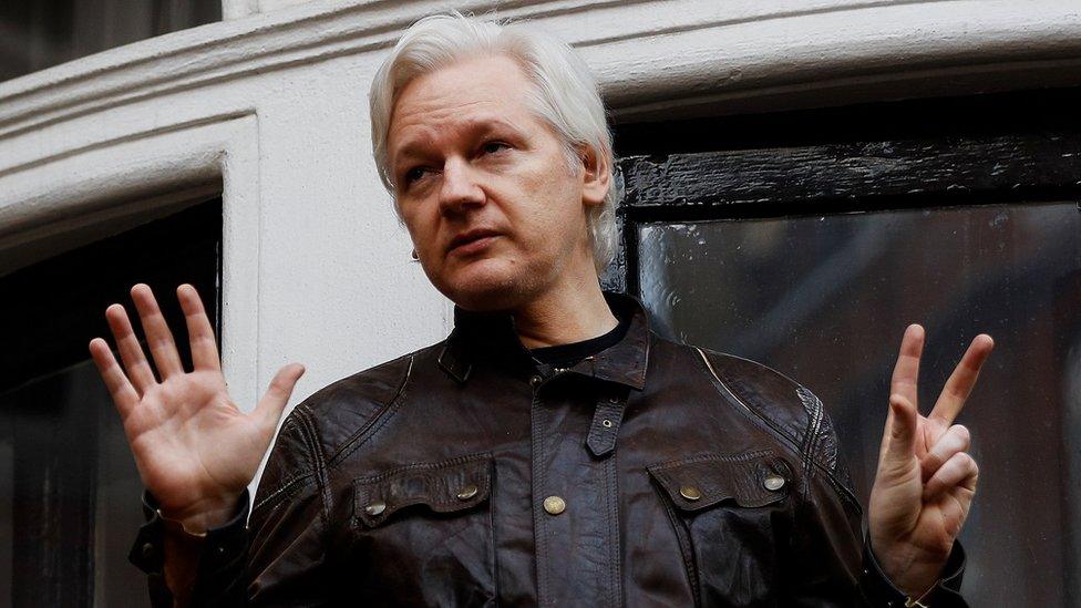 Julian Assange spreads his hands while standing on the balcony of the Ecuadorian embassy