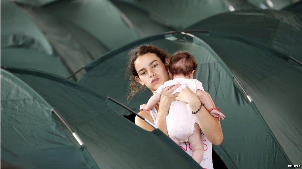 A deported teenager holds a baby amidst tents at a temporary shelter in Villa del Rosario in Colombia on 29 August, 2015.