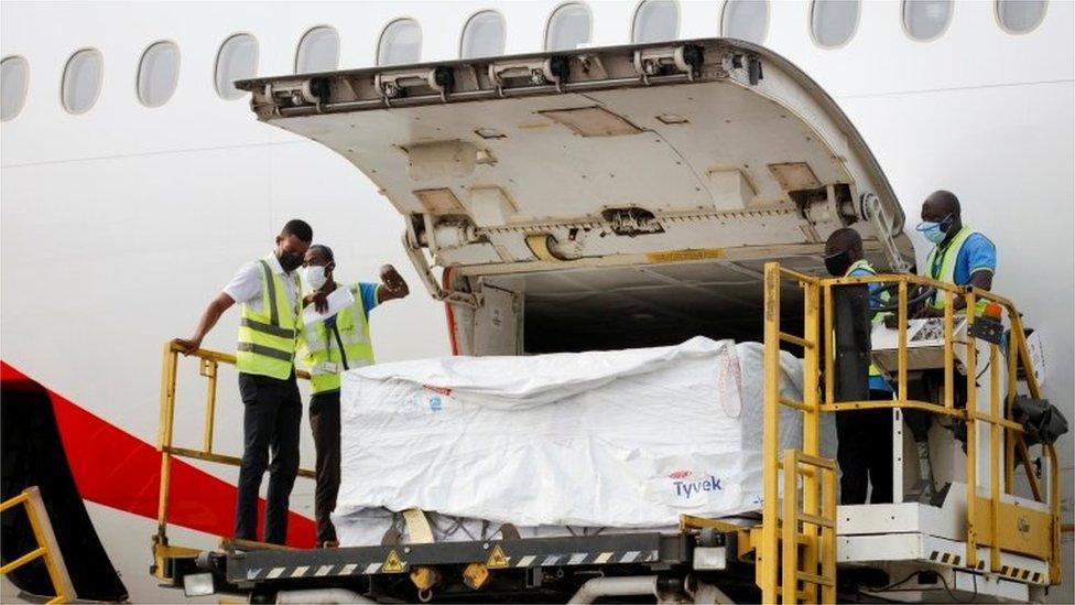 Workers offload boxes of Oxford-AstraZeneca vaccines as the country receives its first batch under Covax scheme, in Accra