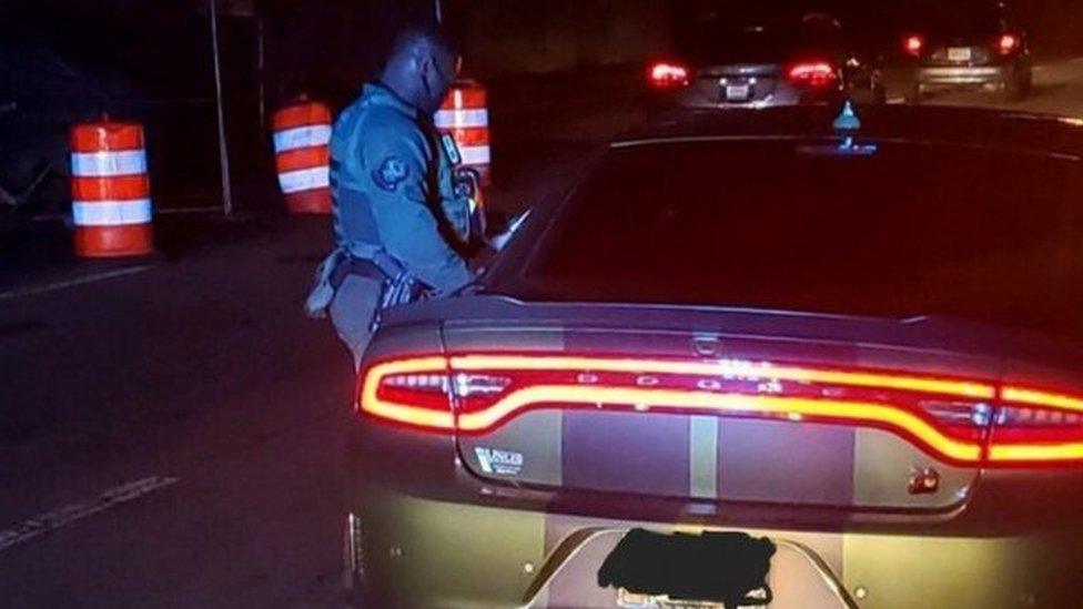 An Atlanta Police officer stands next to a car equipped for street racing, in a police picture posted on Facebook, on 21 December 2020