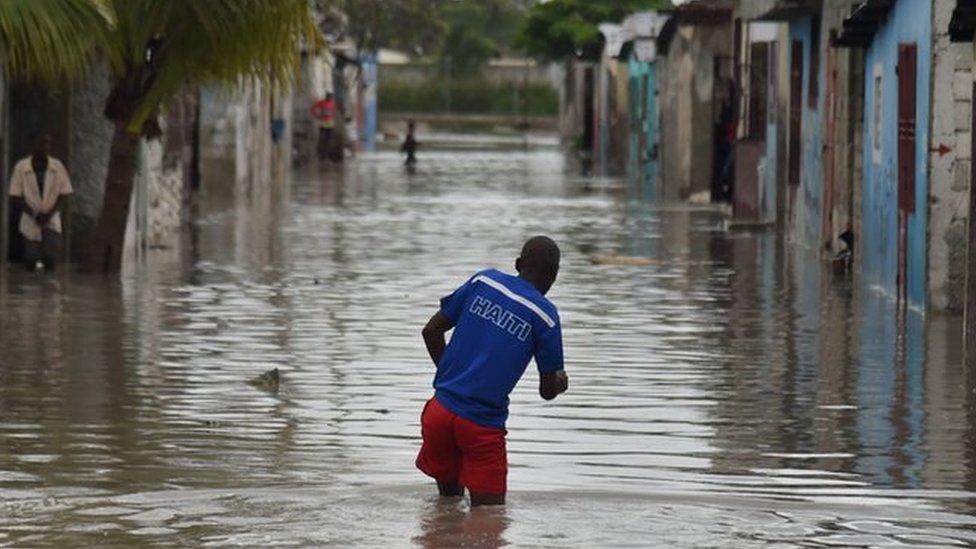 A man walks in a flooded street, in a neighbourhood of the commune of Cite Soleil, in the Haitian Capital Port-au-Prince