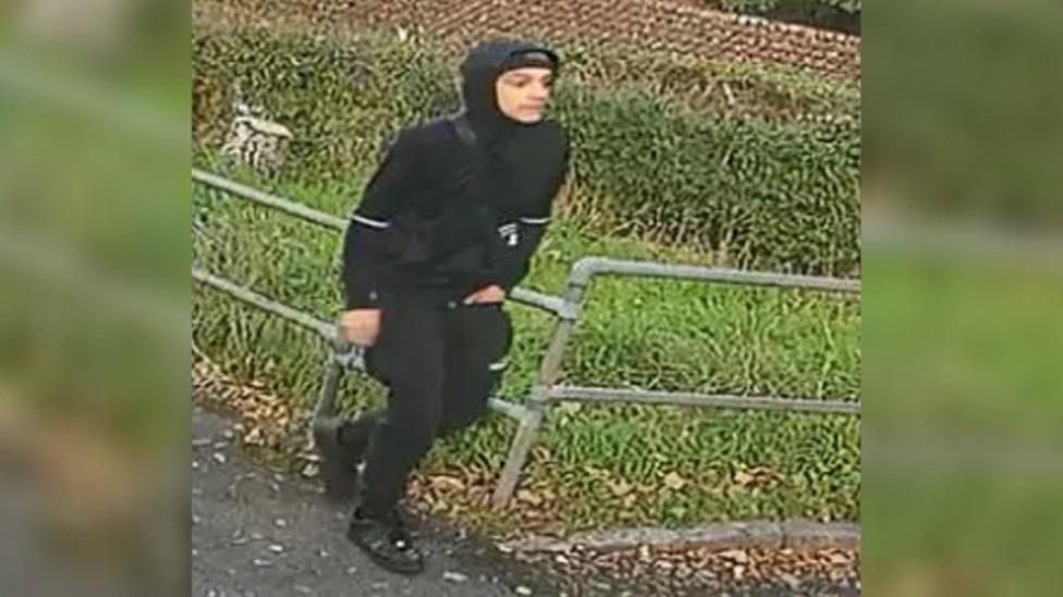 Man in black tracksuit with hood up on CCTV