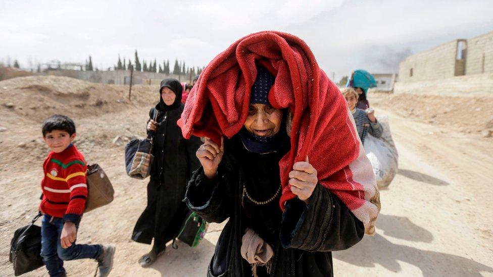 Syrian civilians evacuated from the Eastern Ghouta enclave pass with belongings through the corridor opened by government forces in Hawsh al-Ashaari, east of the enclave town of Hamouria on the outskirts of the capital Damascus on March 15, 2018