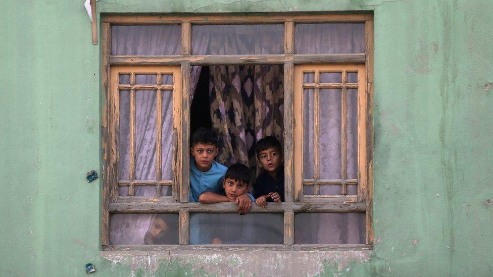 Afghan children looking out of a window