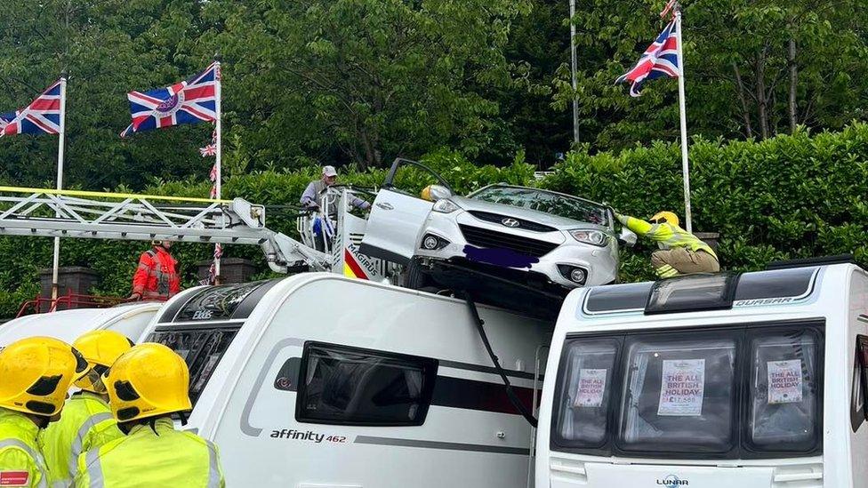 A car stuck on top of two caravans