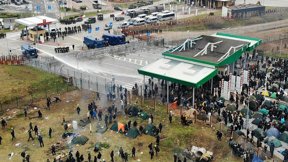 Polish servicemen use tear gas and water jets to disperse migrants near the Kuznica crossing