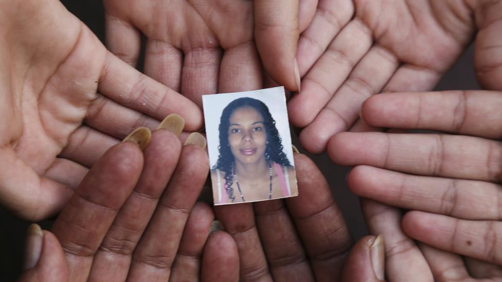 Maribel and her grandchildren hold a photo of Maribel's daughter