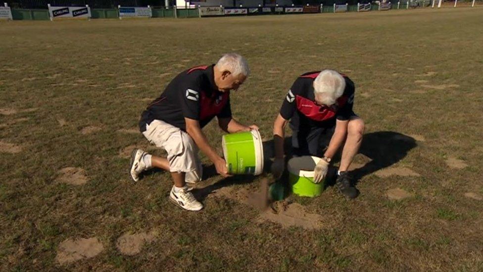 Groundsmen filling holes