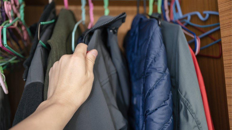 Person looking through a coat cupboard