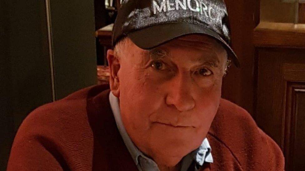 Man looking at camera wearing Menorca cap and Cobblers sweater