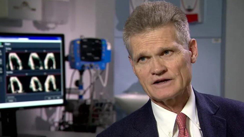 Man in suit and tie sits by imaging machine