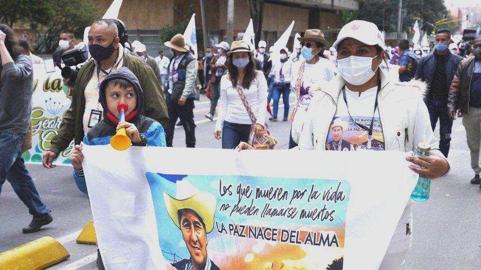 Former Farc fighter Luz Marina Giraldo walks towards the centre of Colombia's capital, carrying a banner with her partner's image.