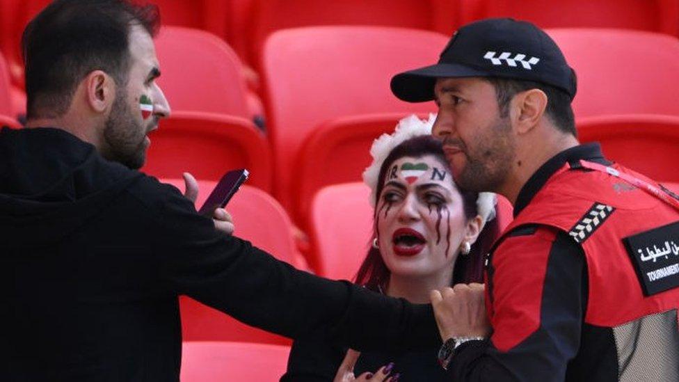 Security staff speak with fans holding up a shirt with the name of Mahsa Amini and a flag advocating for women's rights during the FIFA World Cup Qatar 2022 Group B match between Wales and IR Iran at Ahmad Bin Ali Stadium on November 25, 2022 in Doha, Qatar. People have continued demonstrating in Iran over the death of Mahsa Amini in September.