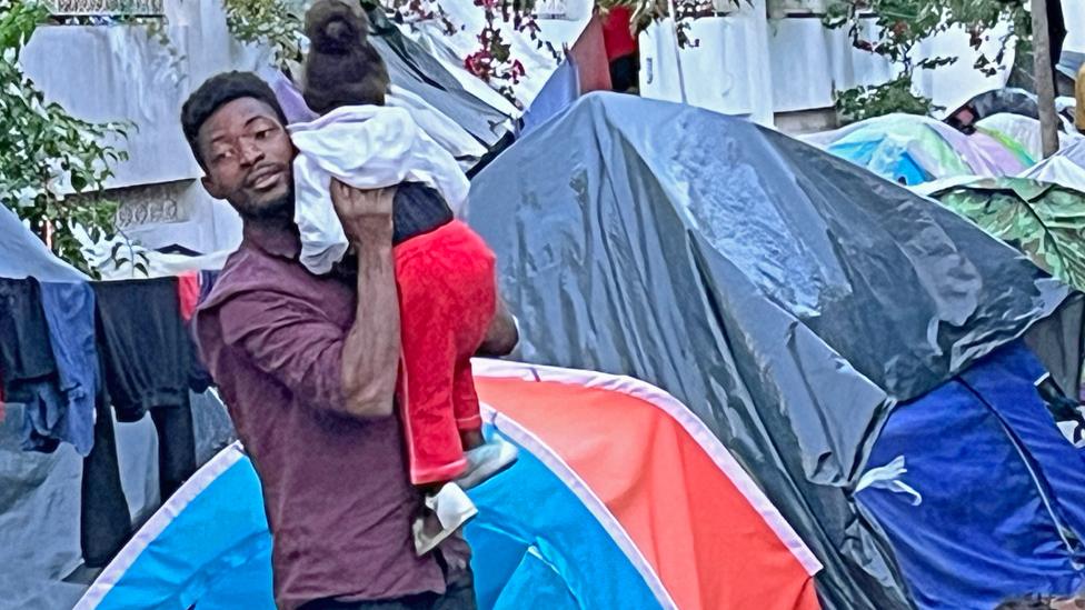 A man holding a child outside tents in Tunisia