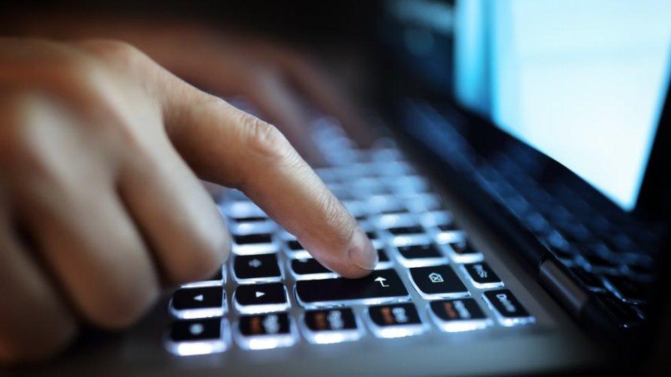 Hands on laptop keyboard in the dark