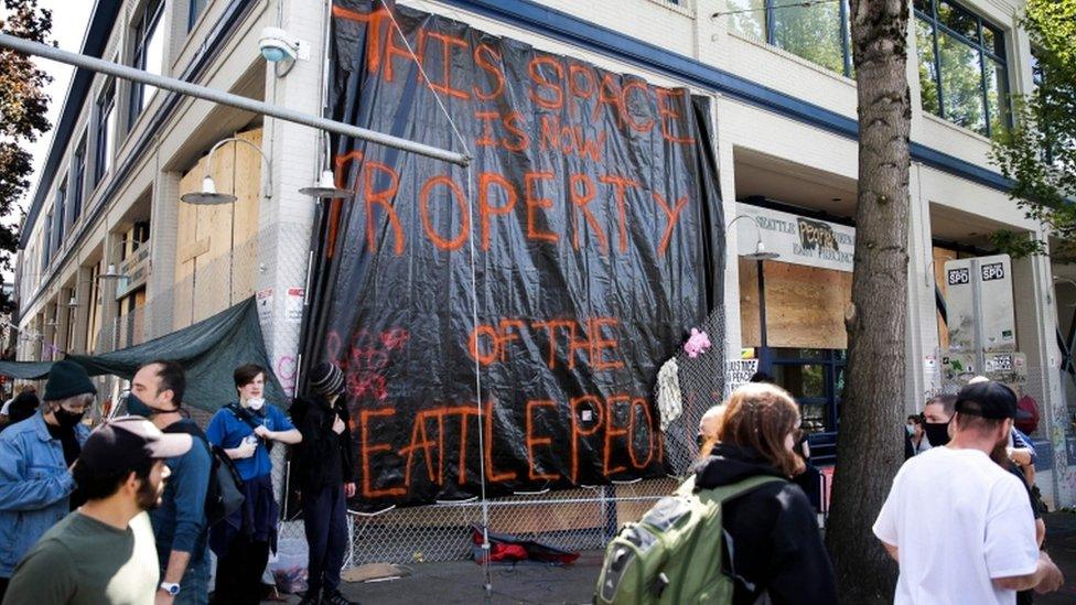 A sign reading 'This space is now property of the Seattle people' hangs over the closed Seattle Police Department's East Precinct