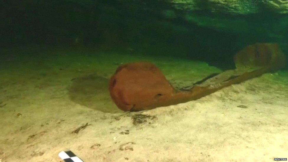 Wooden canoe at bottom of pool in cenote