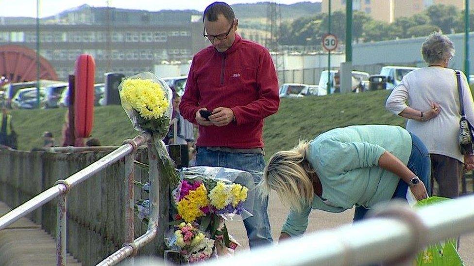 People looking at flowers at the scene