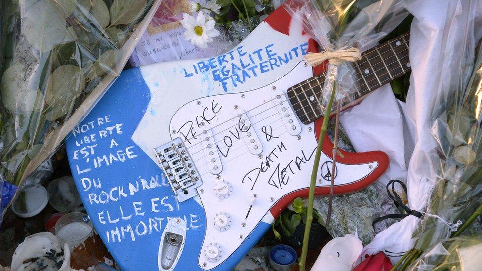 A guitar painted in the colours of the French flag, with the words "Peace, love and death metal" inscribed.