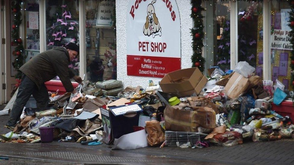 Man placing flood-damaged goods outside a shop