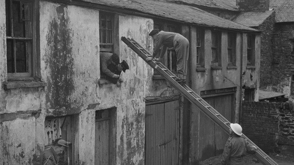 Civil Defence volunteers using a ladder to access a window