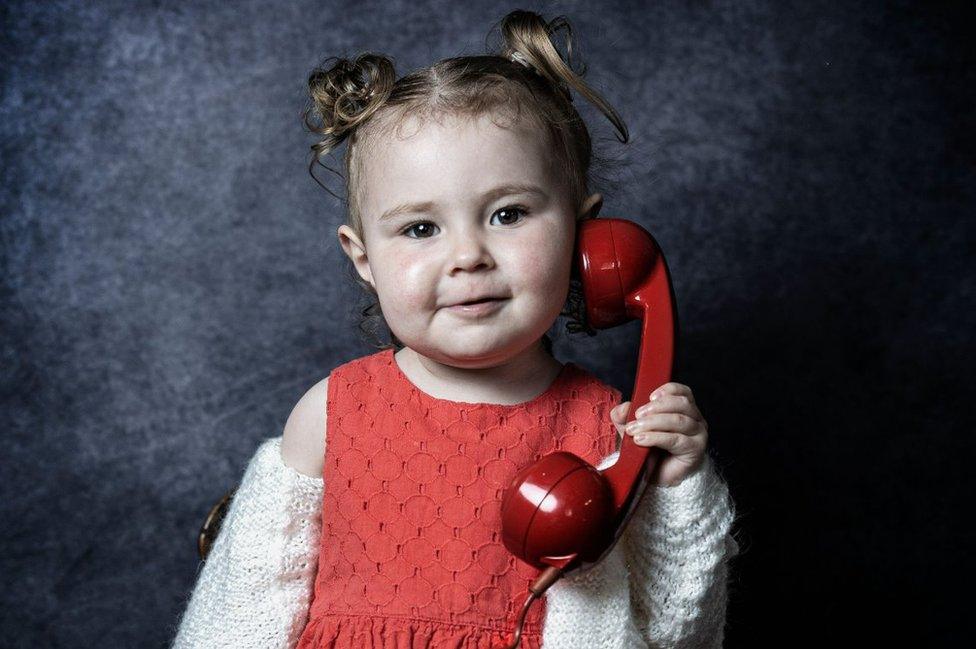 A young girl holds a phone