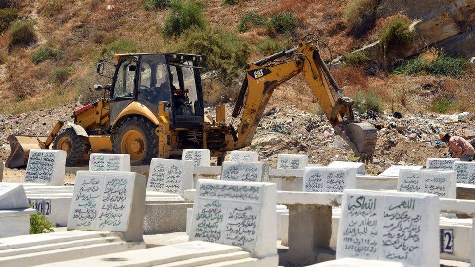 A digger tears the ground up for graves in Tunisia, July 2021