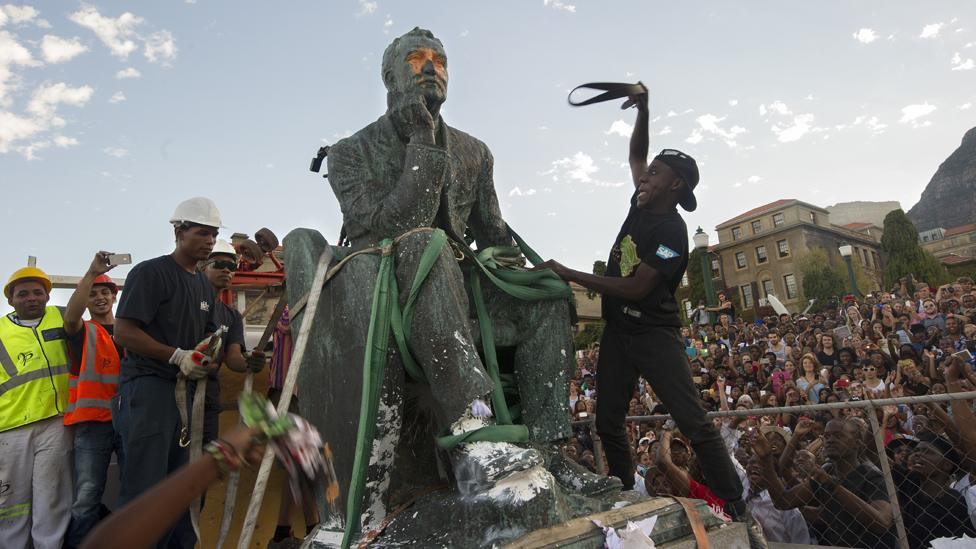 Students attack the defaced statue of British mining magnate and politician, Cecil John Rhodes, as it is removed by a crane from its position at the University of Cape Town on April 9, 2015