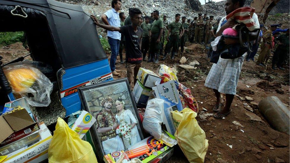 Occupants of a buried house with their possessions - a three-wheeler, their large wedding photograph and some salvaged items at the site of a collapsed garbage mountain in Colombo, Sri Lanka