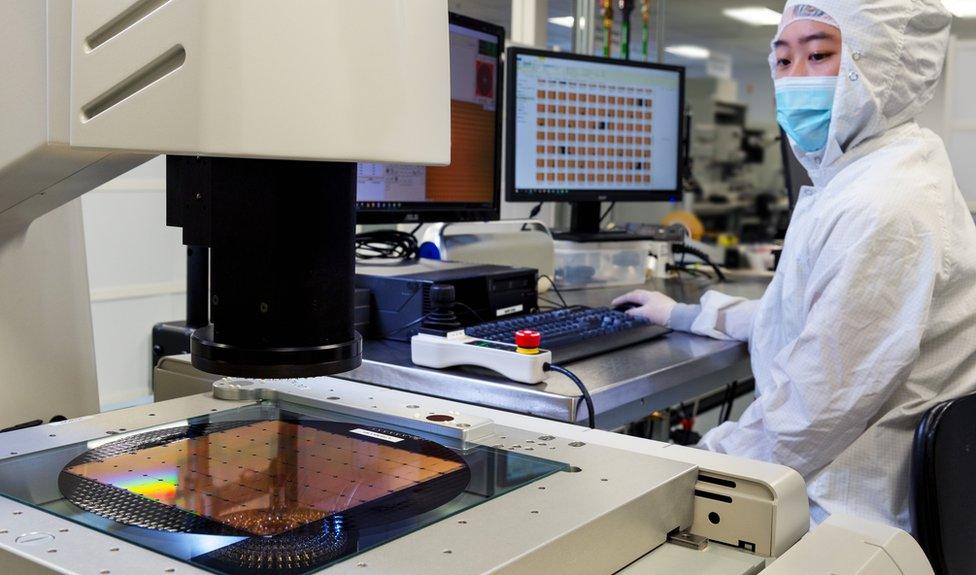 A worker inspects the chips as they are manufactured