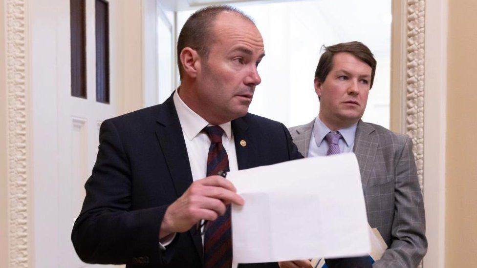 Two men in conversation - one is holding a paper document