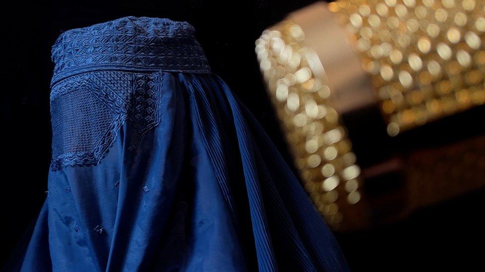 One of the sisters singing under a burka, with a microphone in front