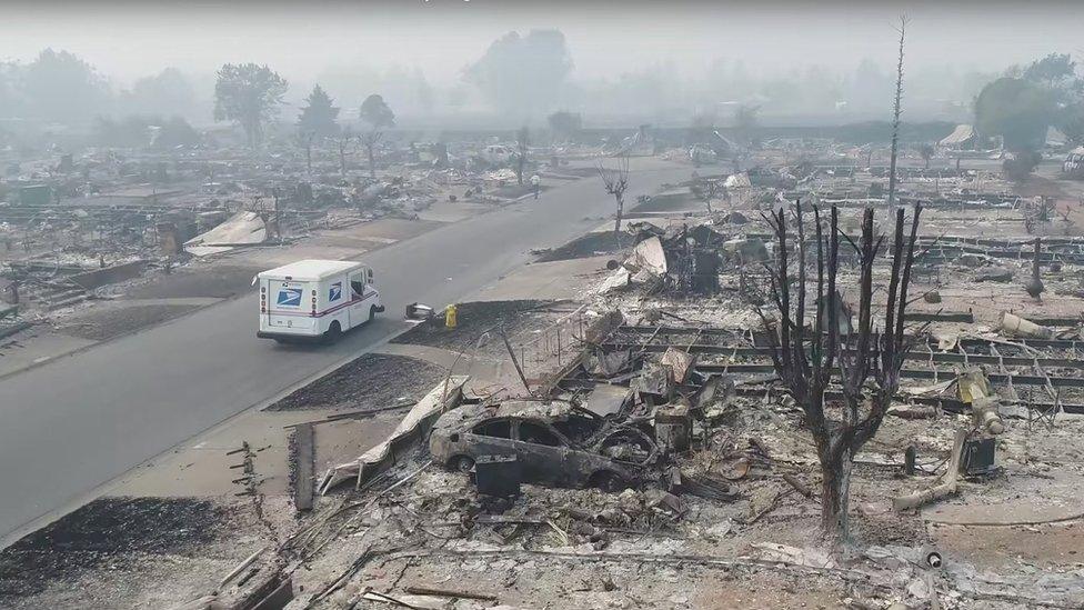 A postman delivers mail in a fire-devastated suburb of Santa Rosa, California