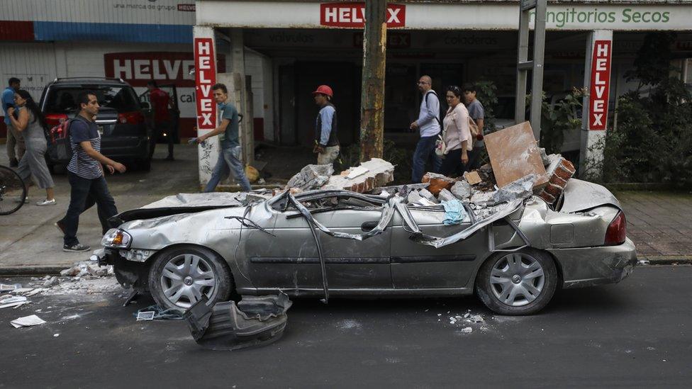 A car crushed under large chunks of rubble