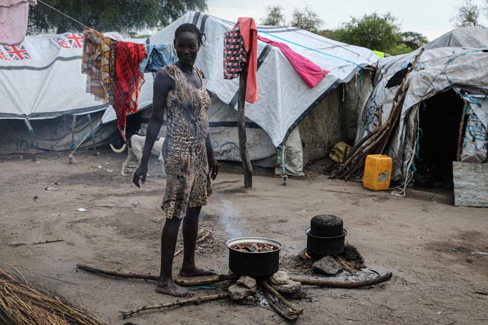 A South Sudanese woman cooks outside her shelter near a flooded area that has been isolated for about a month and a half due to the heavy rain in Pibor Town