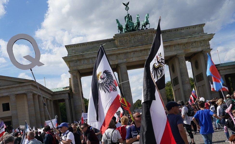 Men carry flags. including of the Kingdom of Prussia and the German Empire, at the Brandenburg Gate during protests against coronavirus-related restrictions and government policy on August 29, 2020 in Berlin, Germany