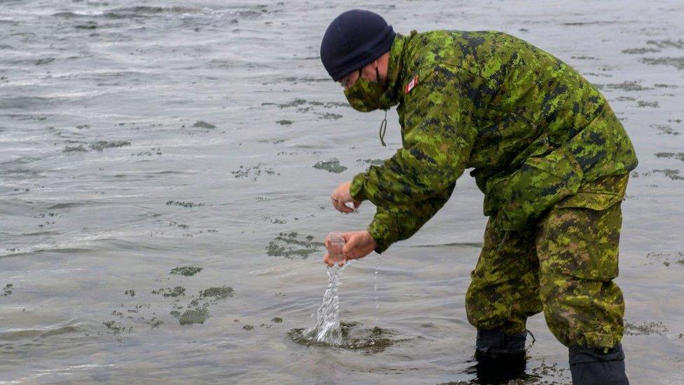 A Canadian armed forces member collecting a water sample