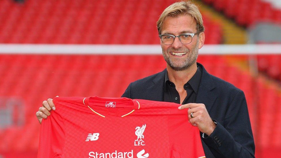 Jurgen Klopp holds up Liverpool shirt